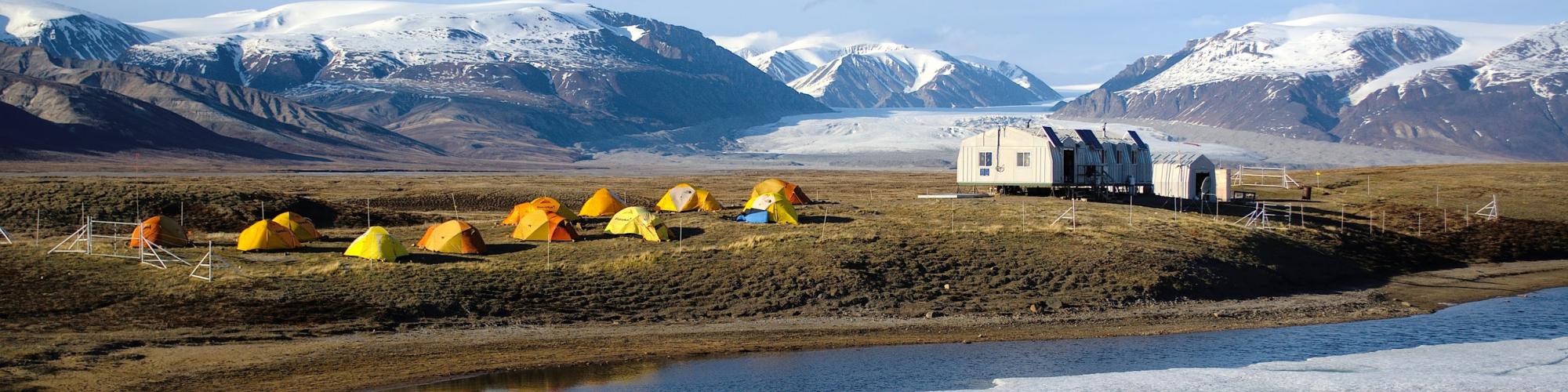 Tentes jaunes entre eau et montagnes glacées